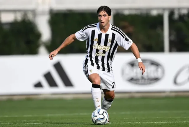 Fabio Miretti in a Juventus home kit dribbling a football on a grass pitch