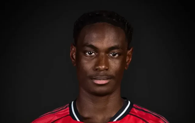 Headshot of Habeeb Ogunneye wearing a red and black Manchester United training kit against a dark background