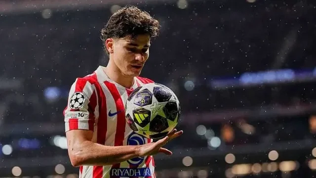 Julian Alvarez wearing an Atletico Madrid jersey holding a Champions League football